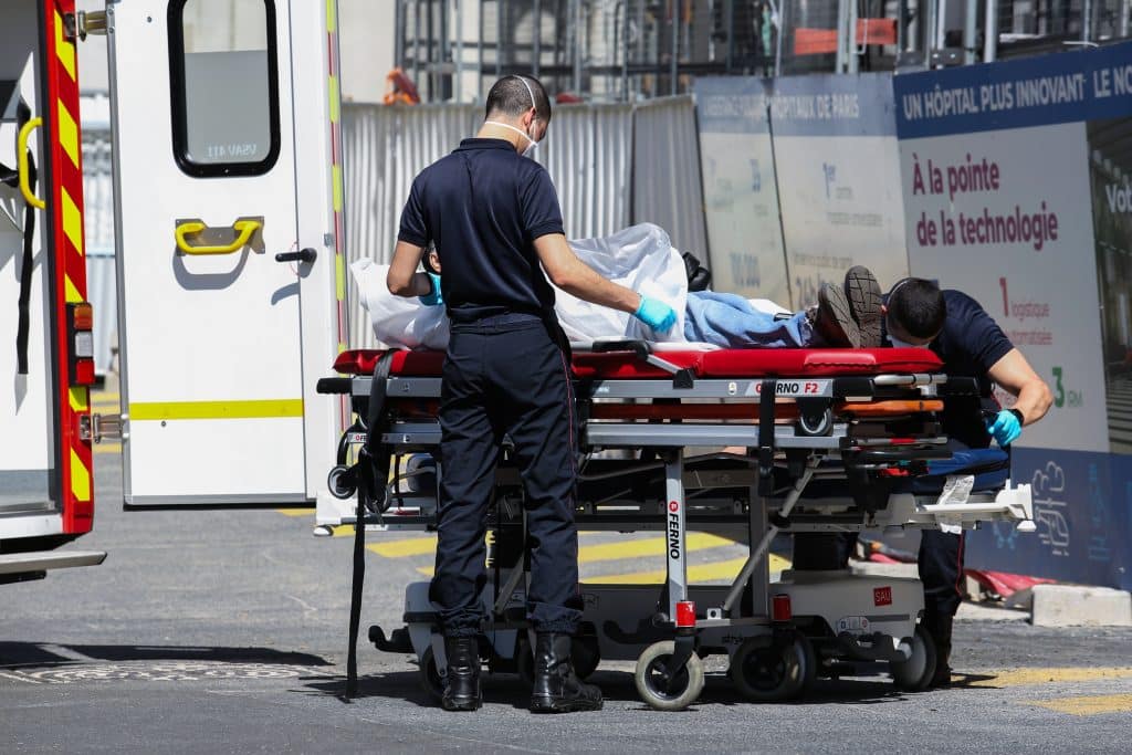 Patient transporté sur un brancard devant un hôpital parisien