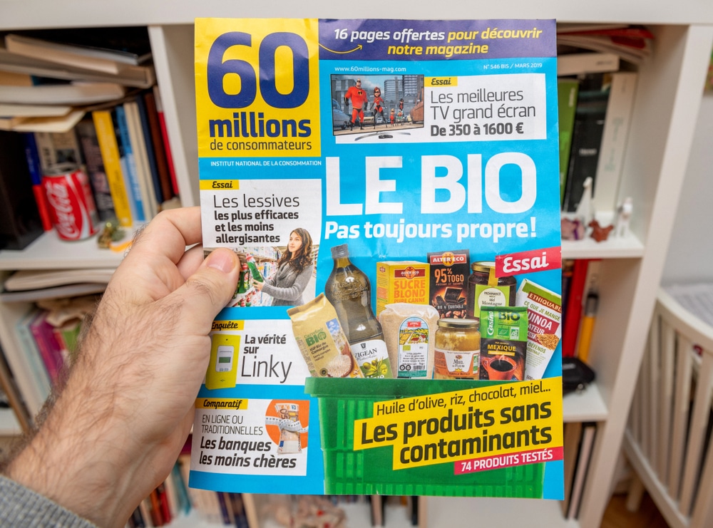 Une main tient un exemplaire du magazine 60 millions de consommateurs