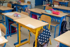 Pupitres d'écoliers avec cartables et trousses dans une salle de classe
