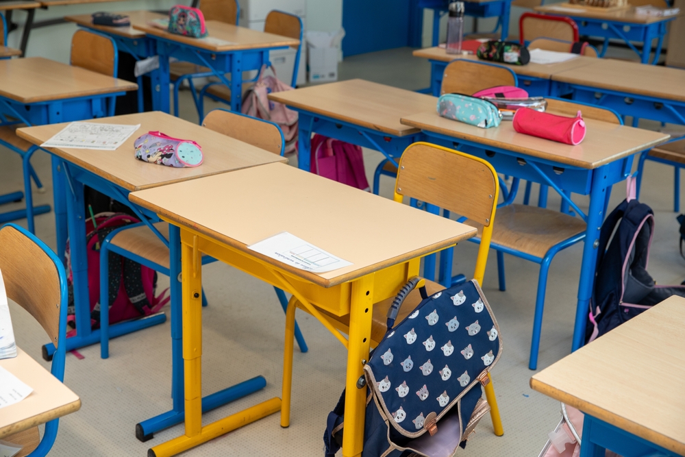 Pupitres d'écoliers avec cartables et trousses dans une salle de classe