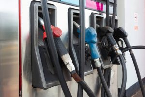 Pistolets de distribution rouge, bleu et noirs accrochés à une pompe à essence en station-service