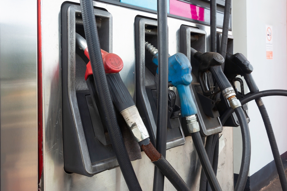 Pistolets de distribution rouge, bleu et noirs accrochés à une pompe à essence en station-service