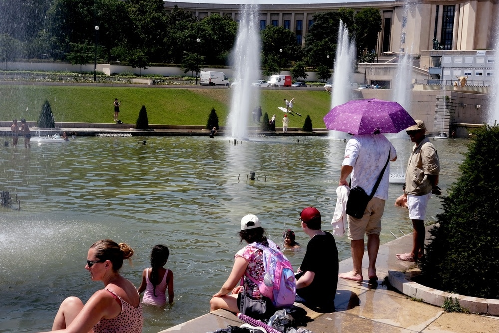 Passants se rafraîchissant dans les bassins du Trocadéro à Paris