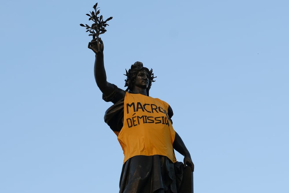 Statue vêtue d'un gilet jaune floqué « Macron Démission »