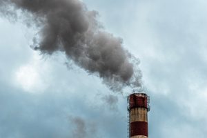 Cheminée industrielle rejetant une épaisse fumée grise dans le ciel