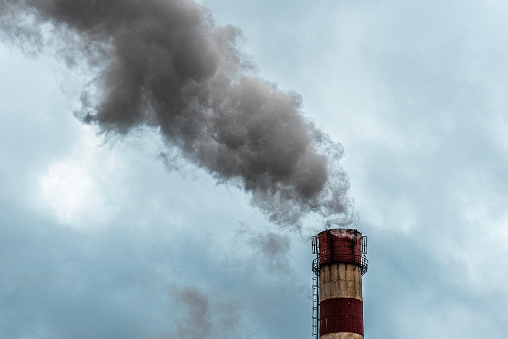 Cheminée industrielle rejetant une épaisse fumée grise dans le ciel